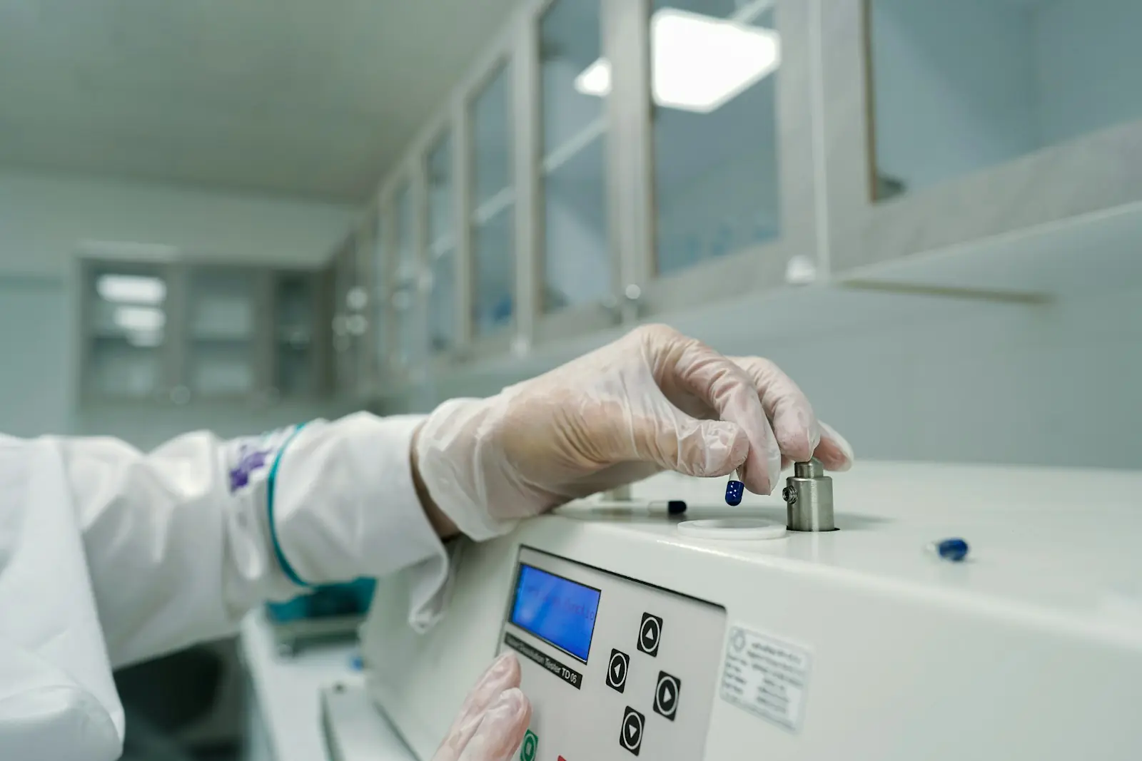Person mit Schutzhandschuhen bedient ein Analysegerät im Labor