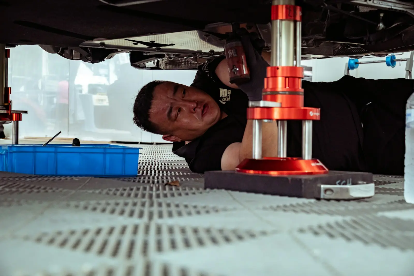 Mechaniker arbeitet unter einem Fahrzeug auf einer Hebebühne